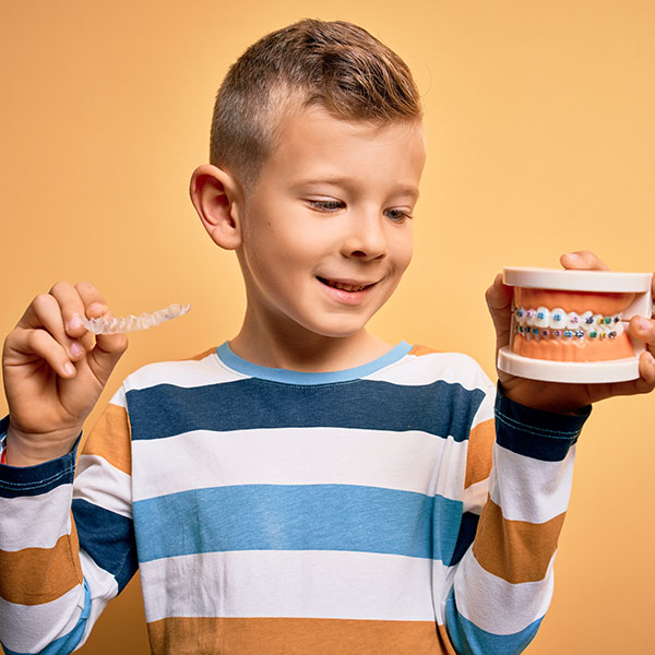 Child holding braces and aligners